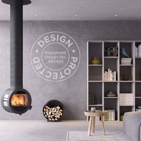 Modernes Wohnzimmer mit hängendem Holzofen, minimalistischem Dekor und einer durch große Fenster sichtbaren Schneelandschaft.