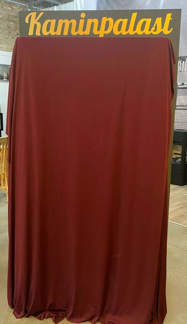 Ein großer kastanienbrauner Vorhang steht vor einem Schild mit der Aufschrift "Kaminpalast" in leuchtend gelben Buchstaben